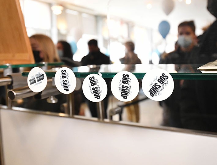 Branding Stickers at Chef Mike’s Sub Shop, students out of focus in the background waiting for lunch.