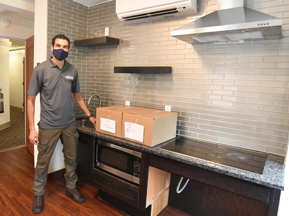 Designated delivery locations within each floor of the residence halls. (Photo: Eileen Barroso) A Campus Services Express team member stands in a residence hall kitchen with two packages.