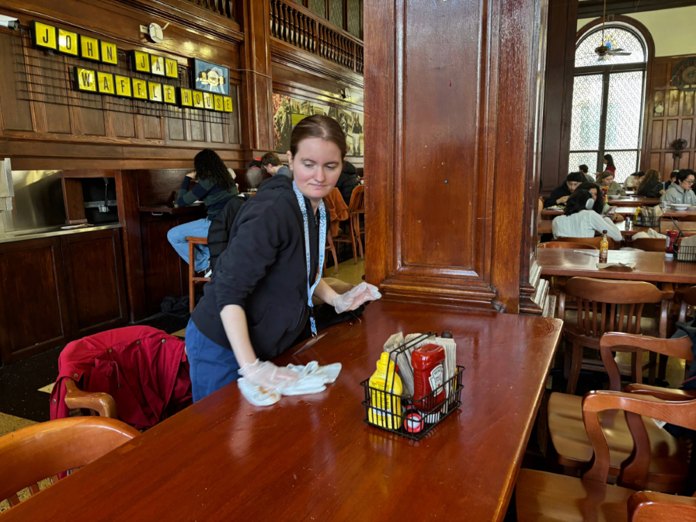 Emma has been coming to campus for a year and now looks forward to her time in Dining. Emma wiping down a table in John Jay