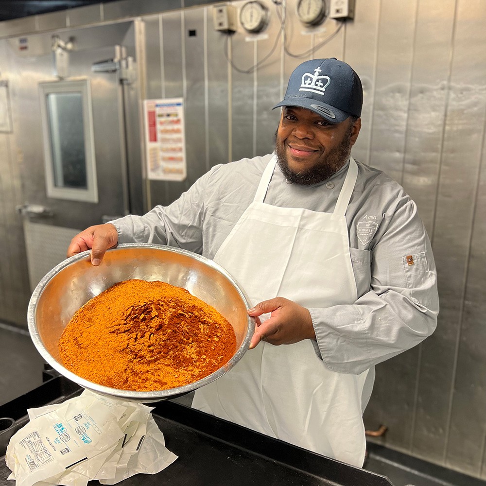 Amin holding a bowl of spices