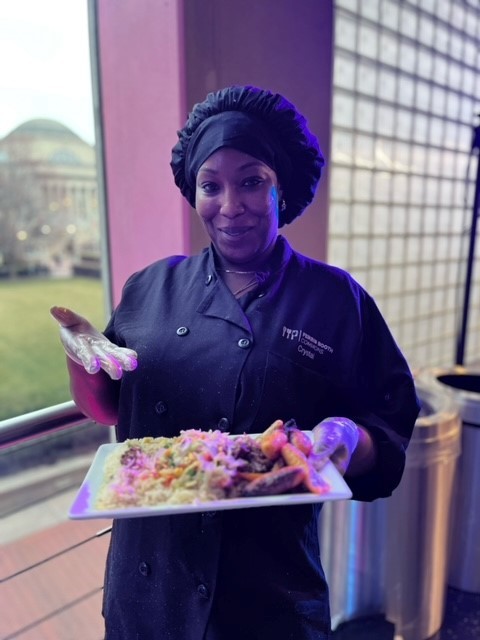 Crystal says, "I made this plate because it reminds me of my grandmother, my mom, my aunts and uncles - thank you for teaching me this growing up!" Crystal holding a plate of curry goat