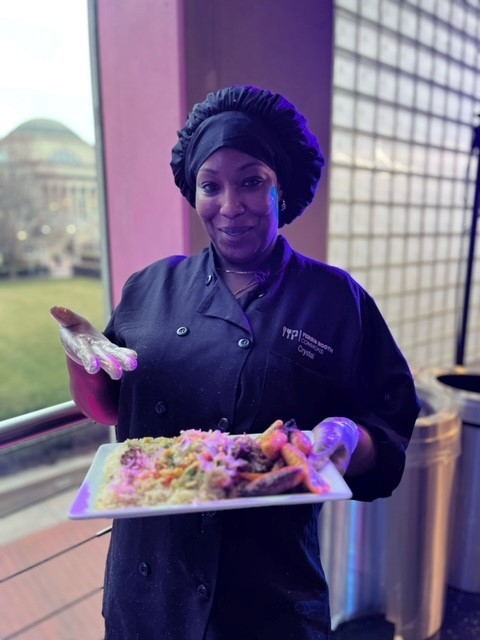 Crystal holding a plate of curry goat