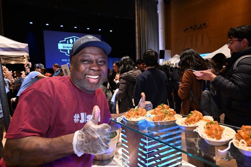 A staff member gives a thumbs up while serving food