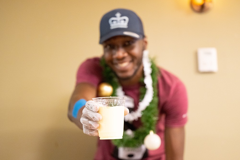 A dining staff member holding a cup of egg nog.