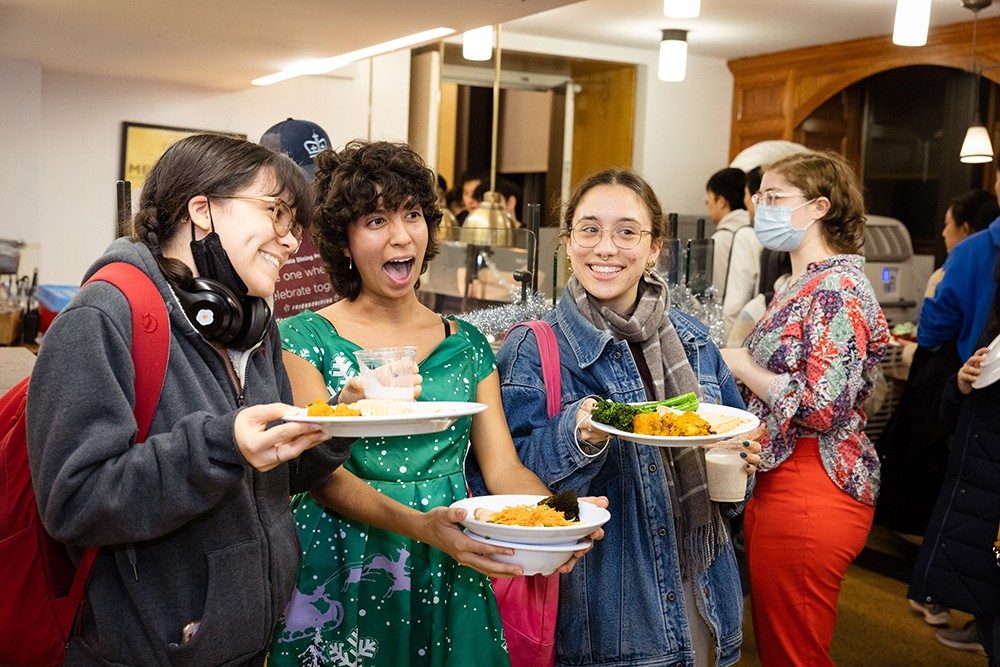 Plates of yummy food = happy, smiling faces Three students in John Jay holding plates of food