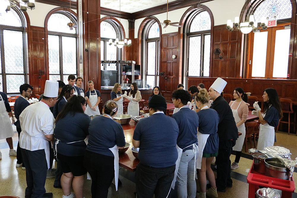 The class standing around tables in John Jay