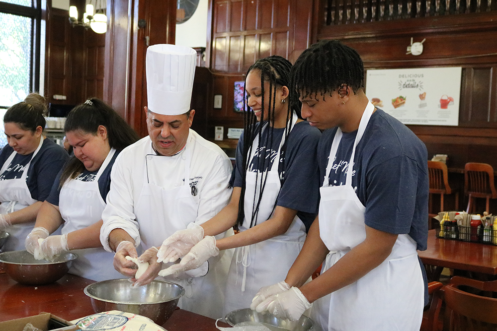 Chef Mike shows students how to knead their mozzarella. Chef Mike showing two students how to knead their mozzarella