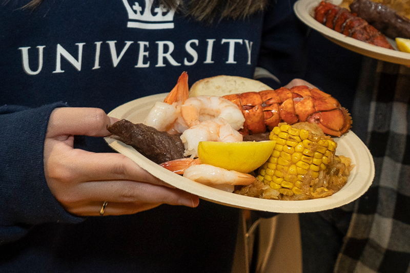 A plate with shrimp, lobster, steak and cord