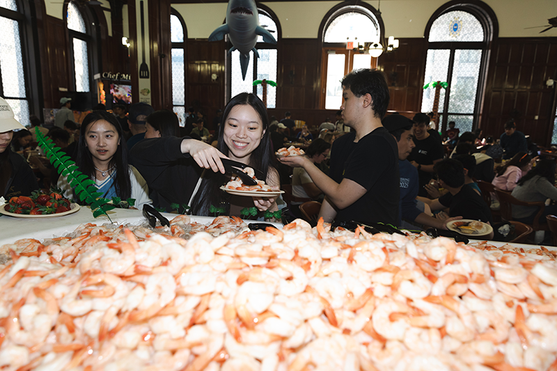 Students serving themselves shrimp out of a boat