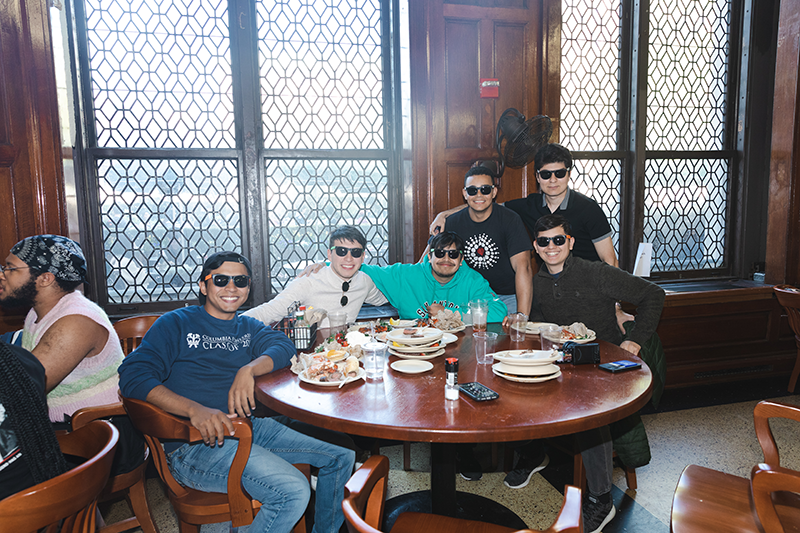 A group of students wearing sunglasses at a table in John Jay