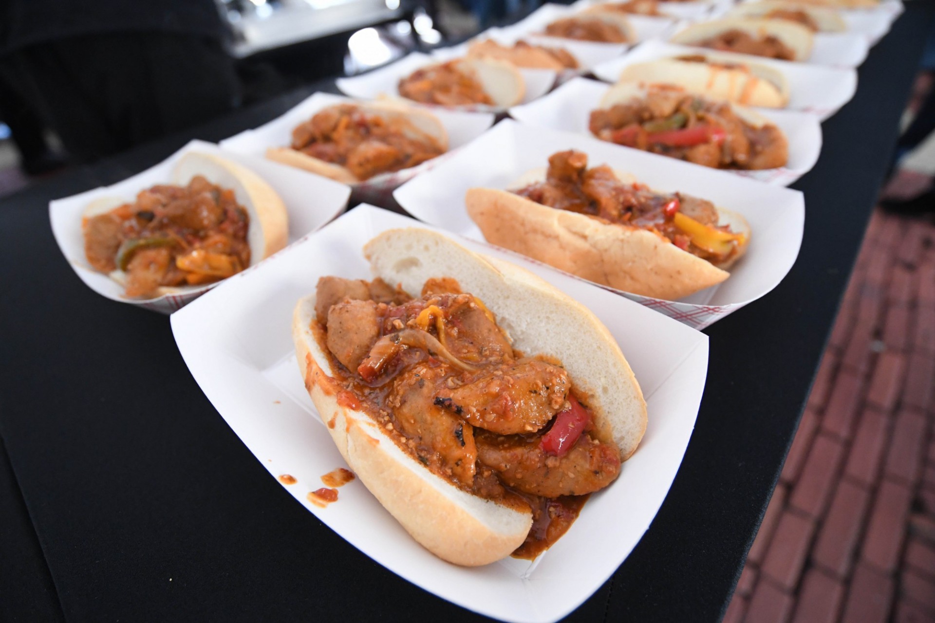 Plates of sausages on rolls with peppers and onions