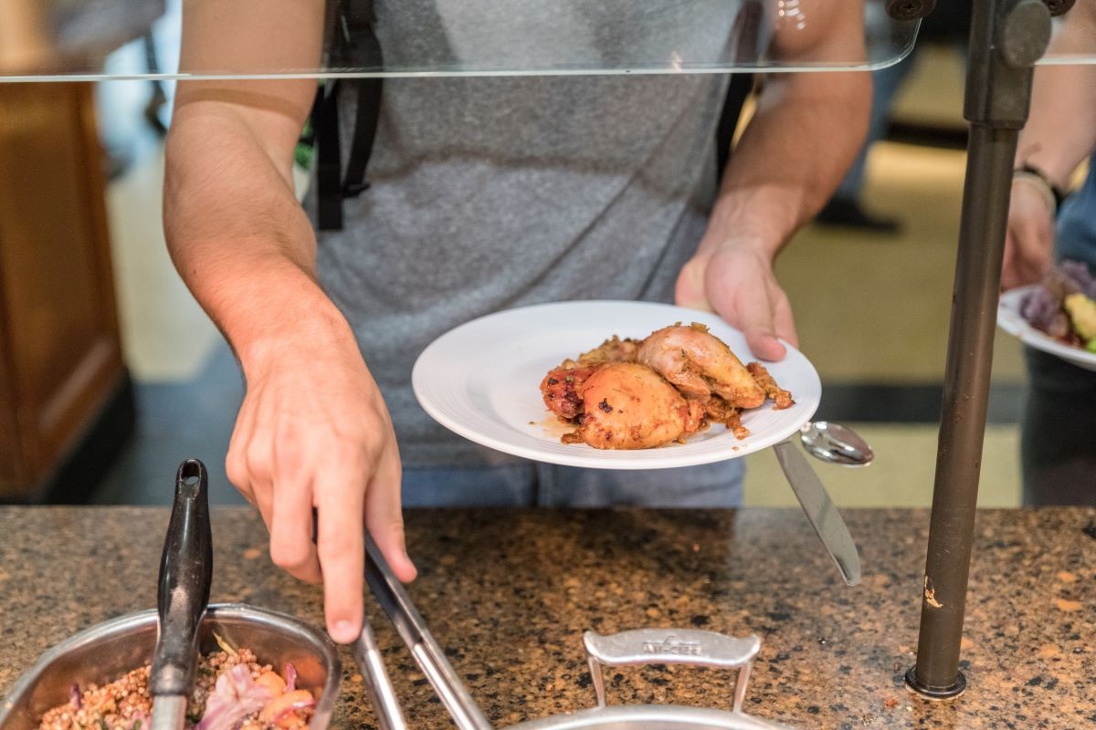 A student serving BBQ chicken onto a plate
