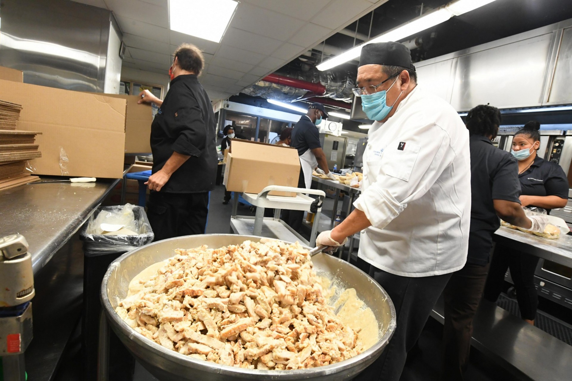 Dining staff member stirs a giant bowl of chicken salad in John Jay Dining Hall