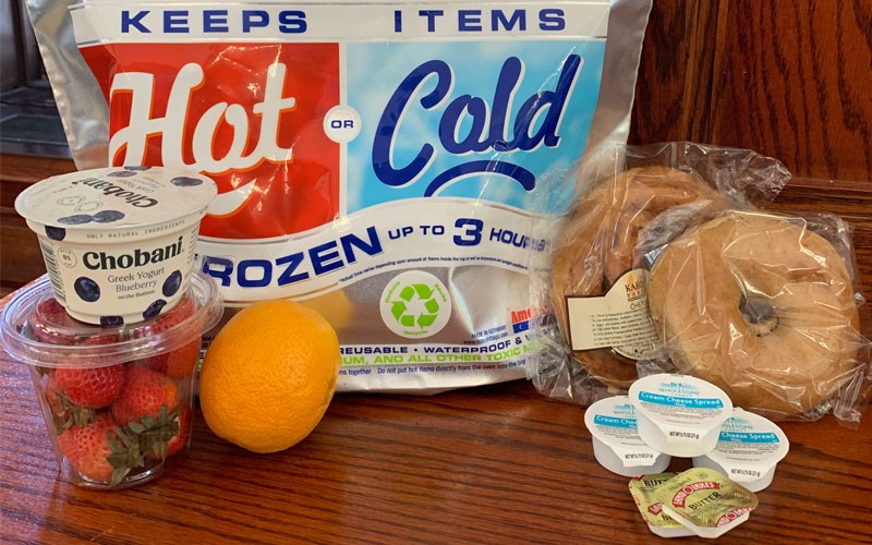 A continental breakfast of yogurt, fresh fruit, and bagels packed for delivery. Continental breakfast of bagels, fruit, and yogurt packed for delivery