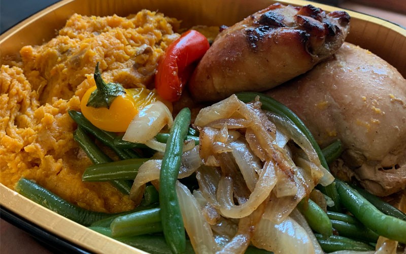 Succulent roast chicken with a side of roast green beans, onions, peppers, and mashed sweet potatoes packed for dinner delivery. Roast chicken dinner packed for delivery