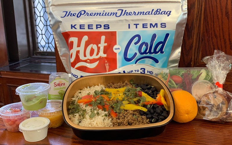 A vegan burrito bowl with all the fixings, packed for lunch delivery. Vegan burrito bowl and condiments packed for delivery