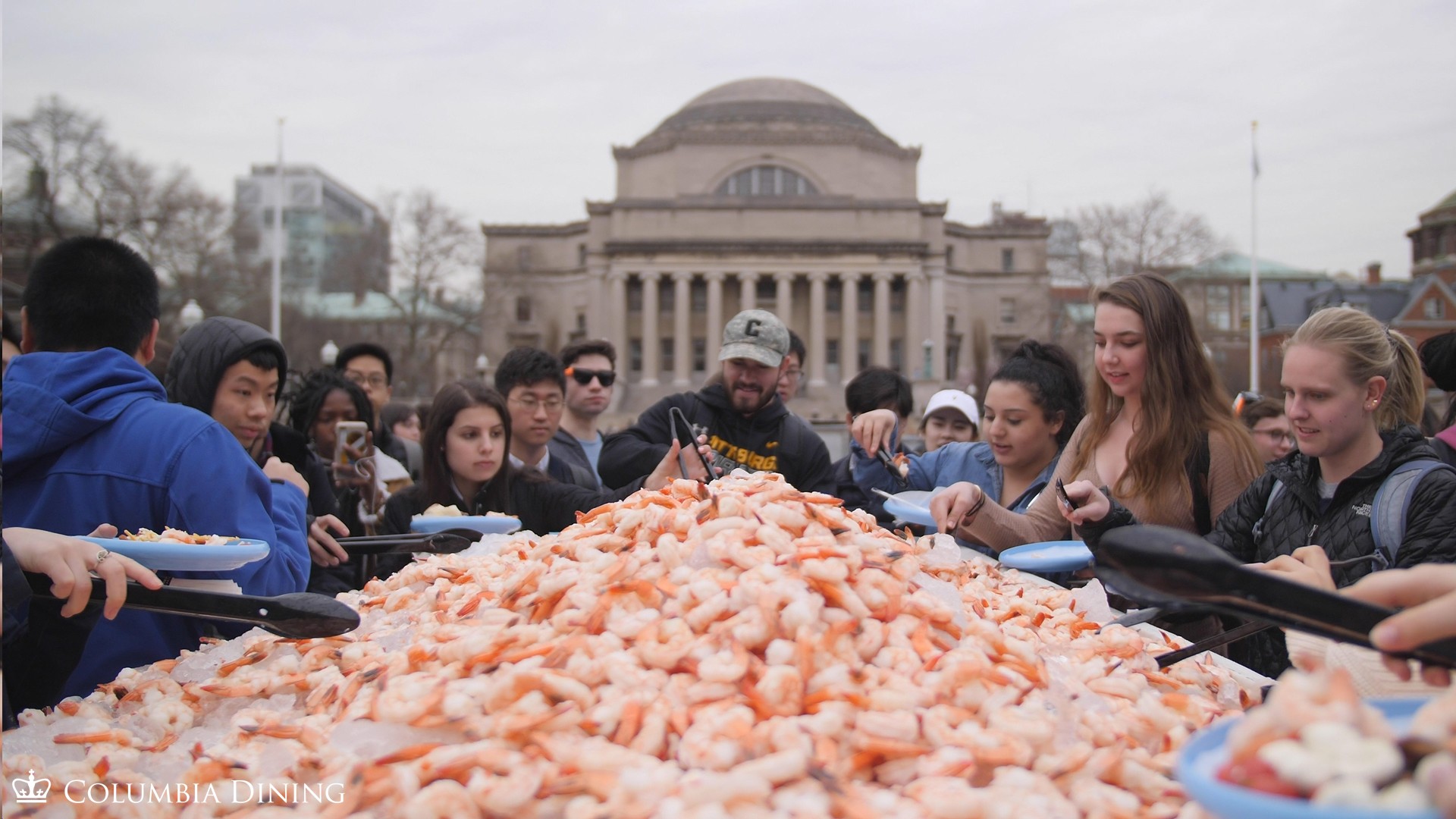 Students serve themselves shrimp from a boat filled with the crustaceans on the lawn in front of Low Library during the annual Surf, Turf and Earth event in 2019.