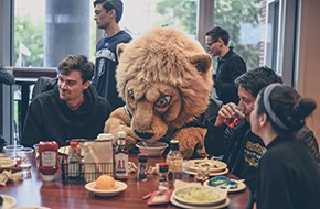 photo of Columbia University's mascot, Roar-ee, eating with a group of students