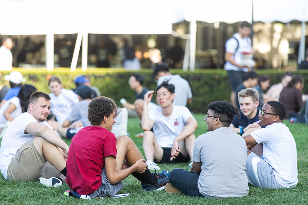 Students sitting outside on South Field lawn in a circle.