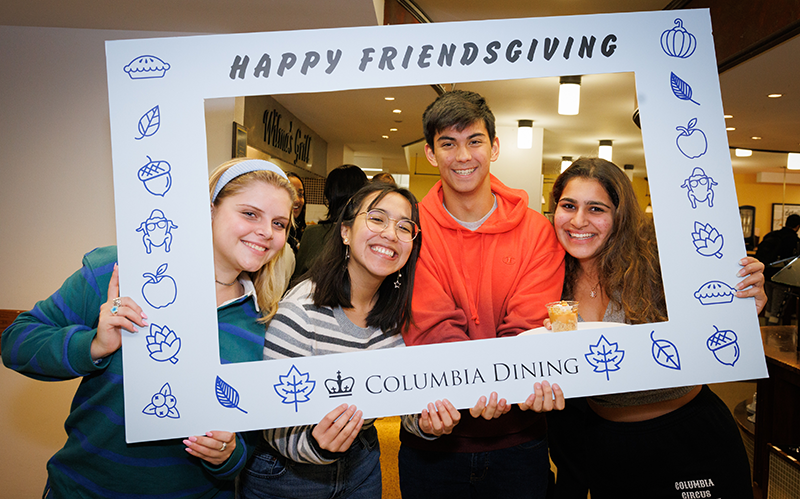 Students hold up a Friendsgiving photo frame in the John Jay servery