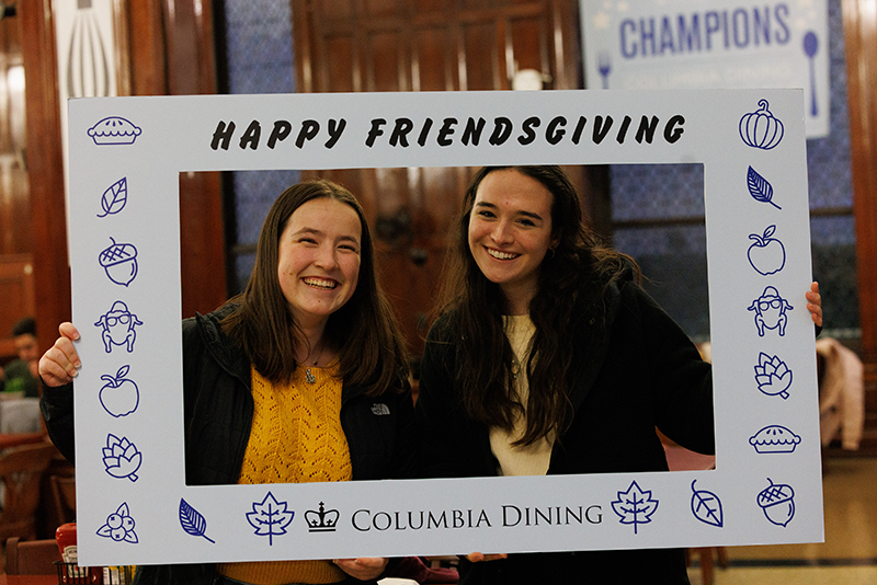 Friendsgiving is for taking pics with friends <3 Students hold up a Friendsgiving photo frame in the John Jay dining hall