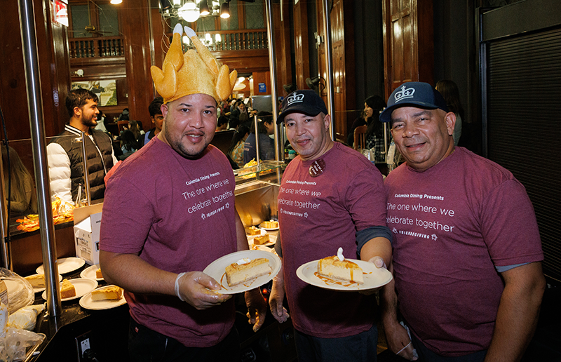 John Jay staff stand at Chef Mike's station holding plates of pumpkin cheesecake