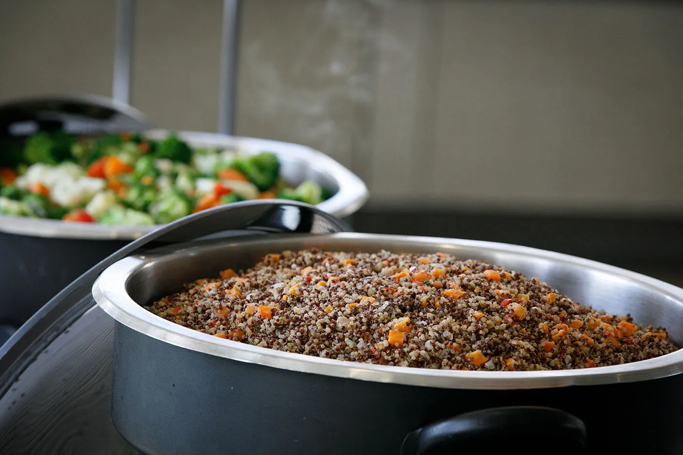 Quinoa pilaf and vegetable medley in black serving dishes