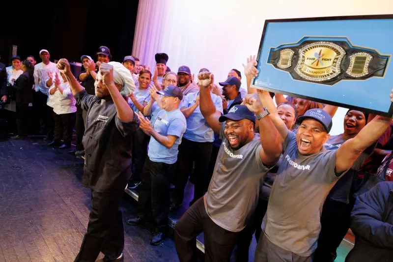 Ferris staff holding the champion belt and cheering