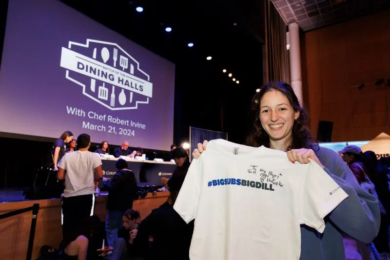 A student holding a shirt signed by Chef Mike