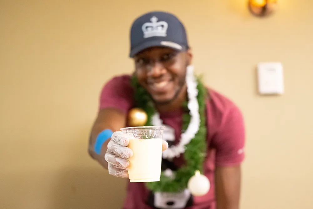 A dining staff member holding a cup of egg nog.