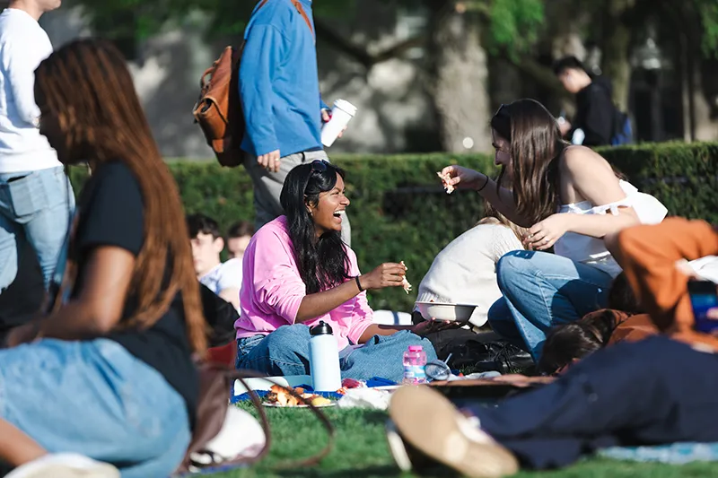 Students holding lobster while sitting on the lawn