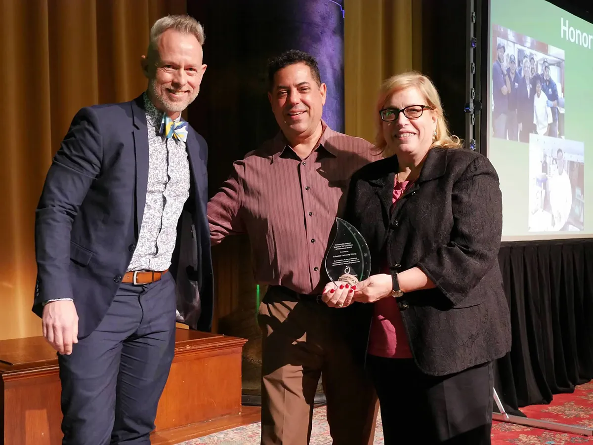 Joseph Greenwell, Michael DeMartino, and Vicki Dunn. Vicki is holding the award.