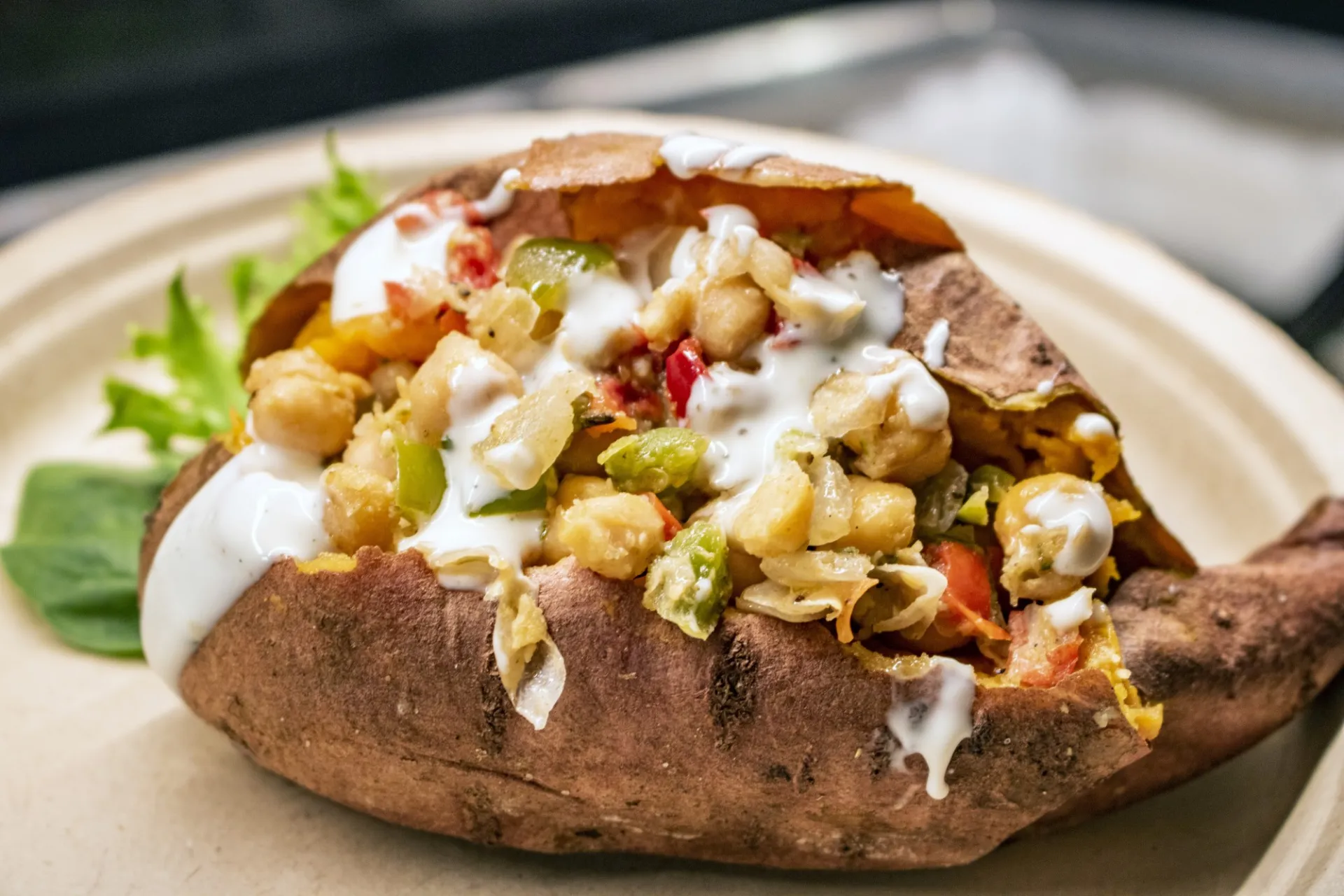 Sweet potato stuffed with plant-based toppings and a vegan creamy dressing
