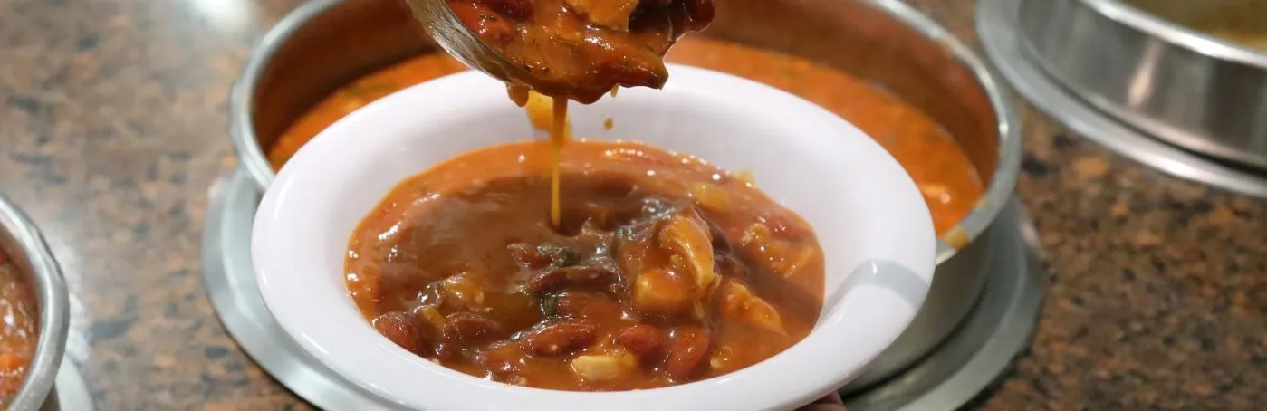 A ladel of soup being poured into a bowl