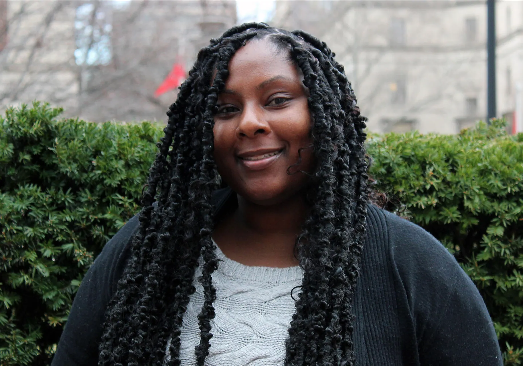 Dionne Douglas photographed on Columbia Campus, green hedges behind
