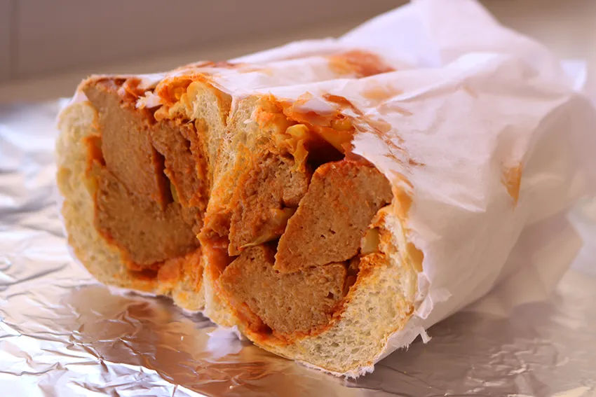 Siracha seitan sub cut in half sitting on aluminum foil